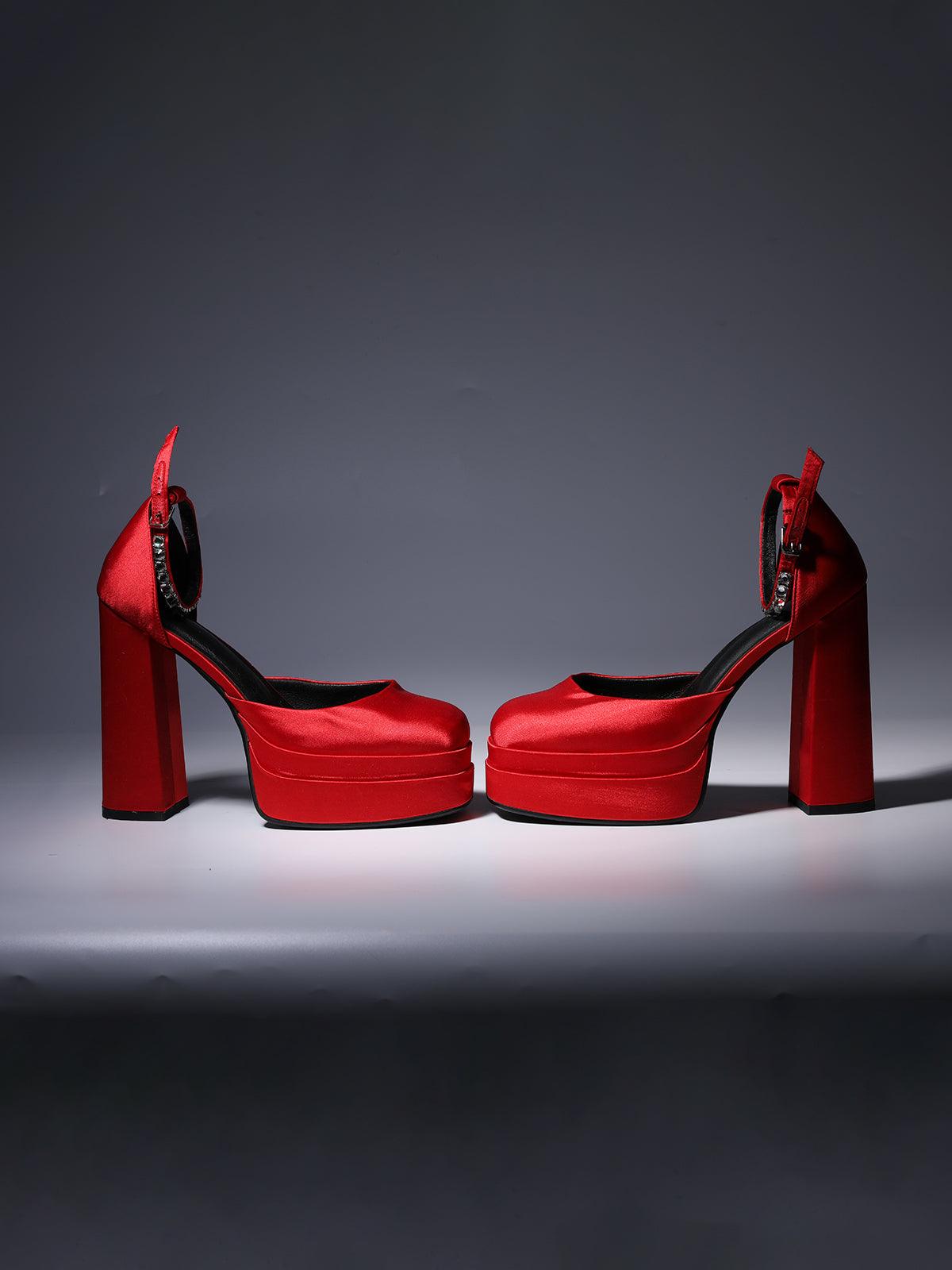 Aspen Satin Platform Pumps displayed on a stylish surface, emphasizing their vibrant red color and sophisticated design.
