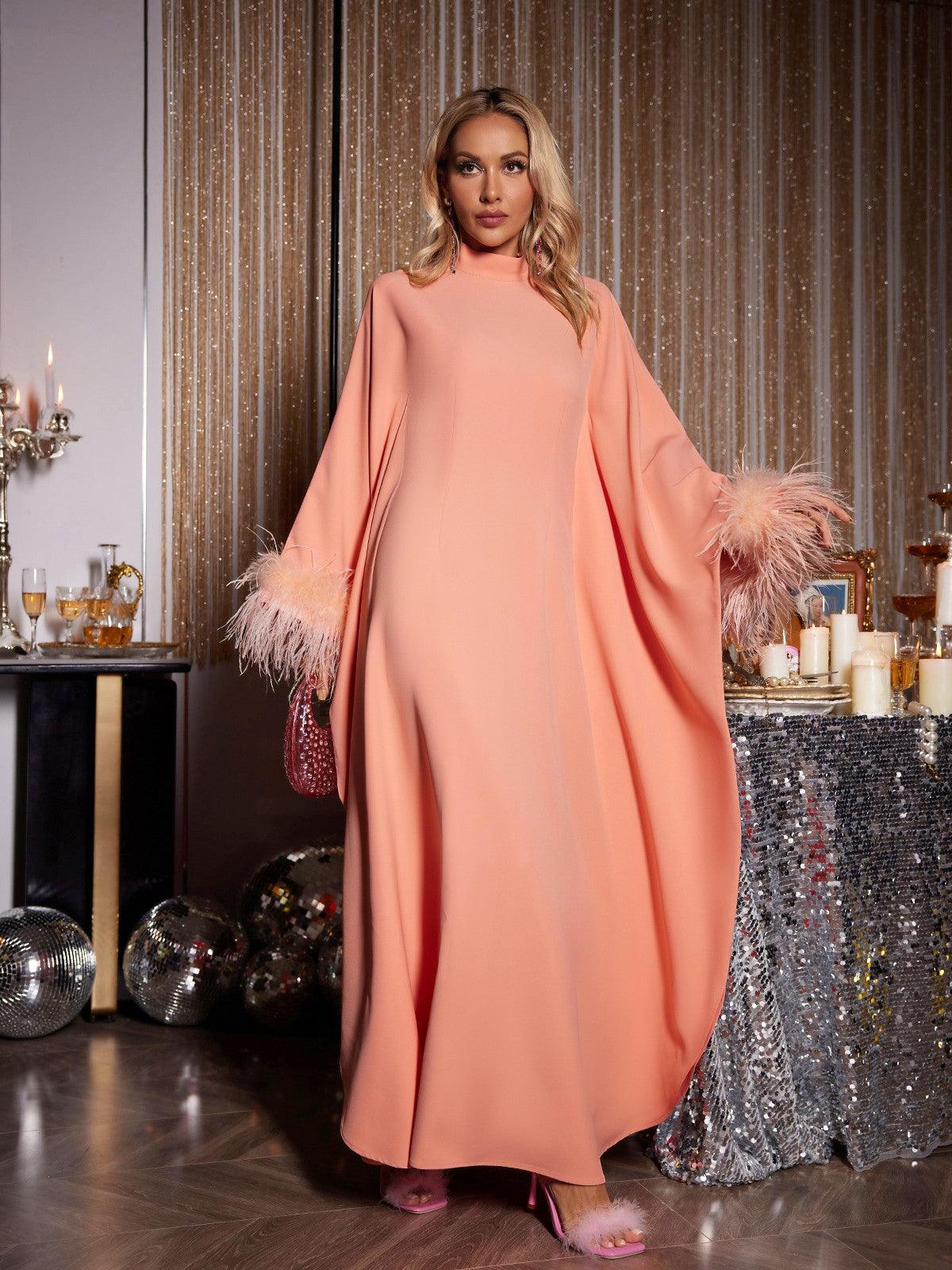 Model wearing the Ceridwen Long Sleeve Feather Maxi Dress in orange at a wedding, showcasing its elegant flow and stylish design.