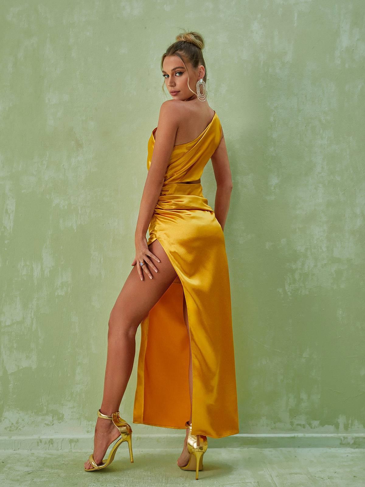 Elegant gold one shoulder cutout maxi dress with a ruched waist and split skirt, perfect for special occasions.
