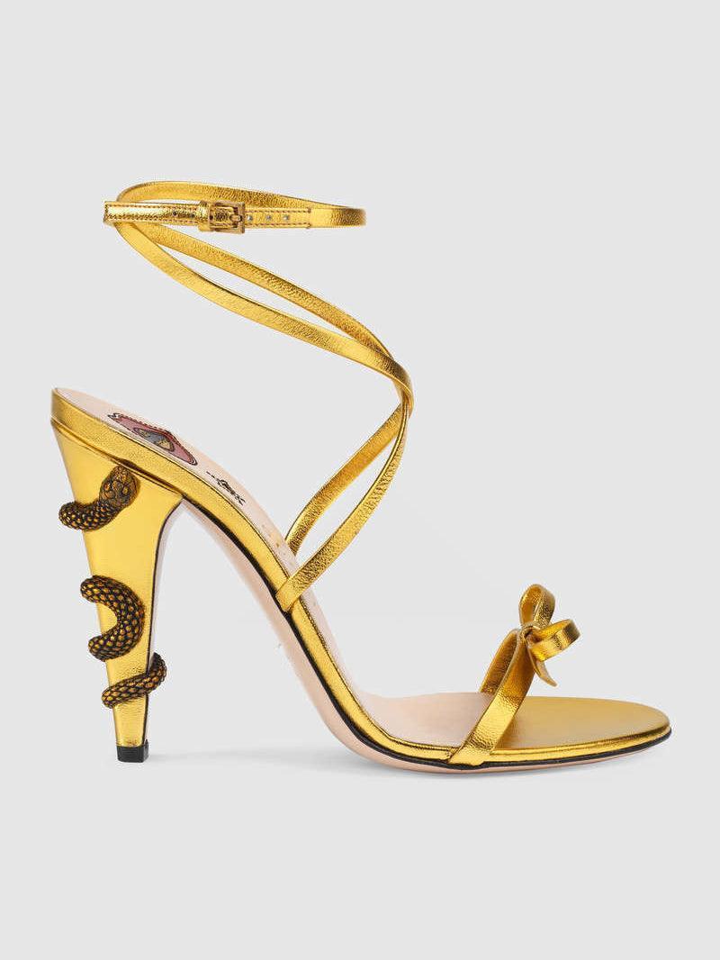 Juliette Metallic Snake Heel Sandals in Gold featuring a stylish ankle strap and unique snake motif.