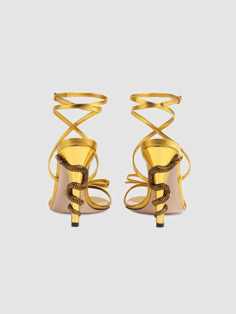 Juliette Metallic Snake Heel Sandals in Gold featuring a stylish ankle strap and unique snake motif.