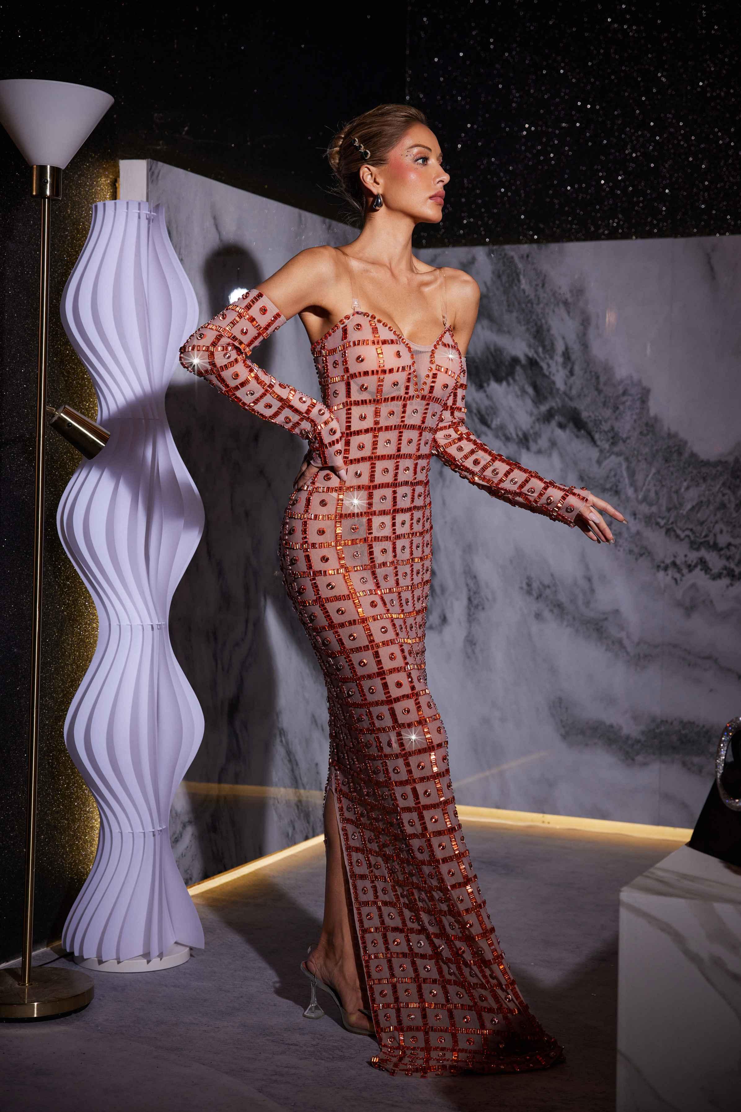Stunning model in a nude Kieran Rhinestone Mesh Maxi Dress.  The strapless, sparkly maxi dress features intricate rhinestone detailing and a flowing mesh skirt. Perfect for prom or an elegant evening event.