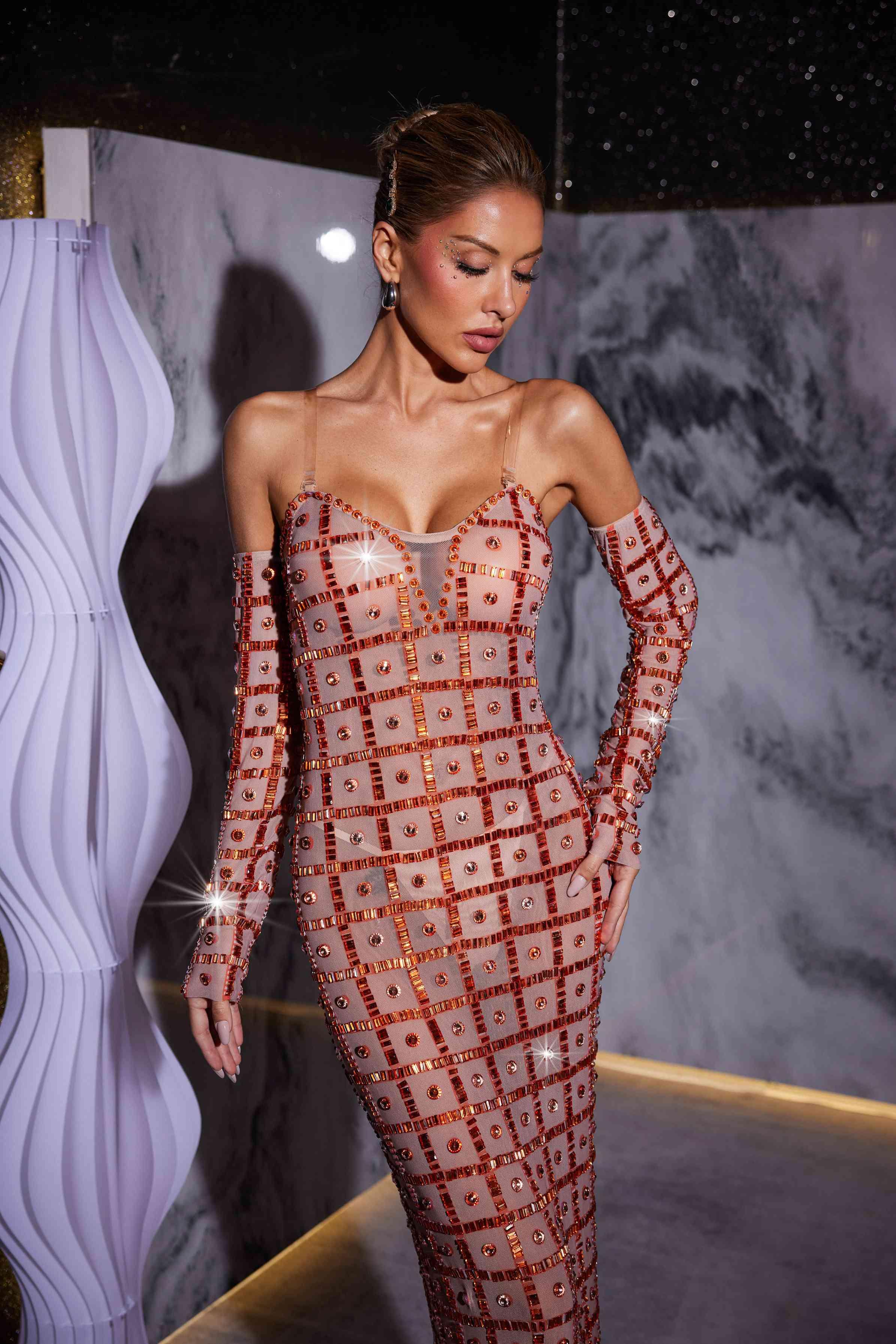 Stunning model in a nude Kieran Rhinestone Mesh Maxi Dress.  The strapless, sparkly maxi dress features intricate rhinestone detailing and a flowing mesh skirt. Perfect for prom or an elegant evening event.