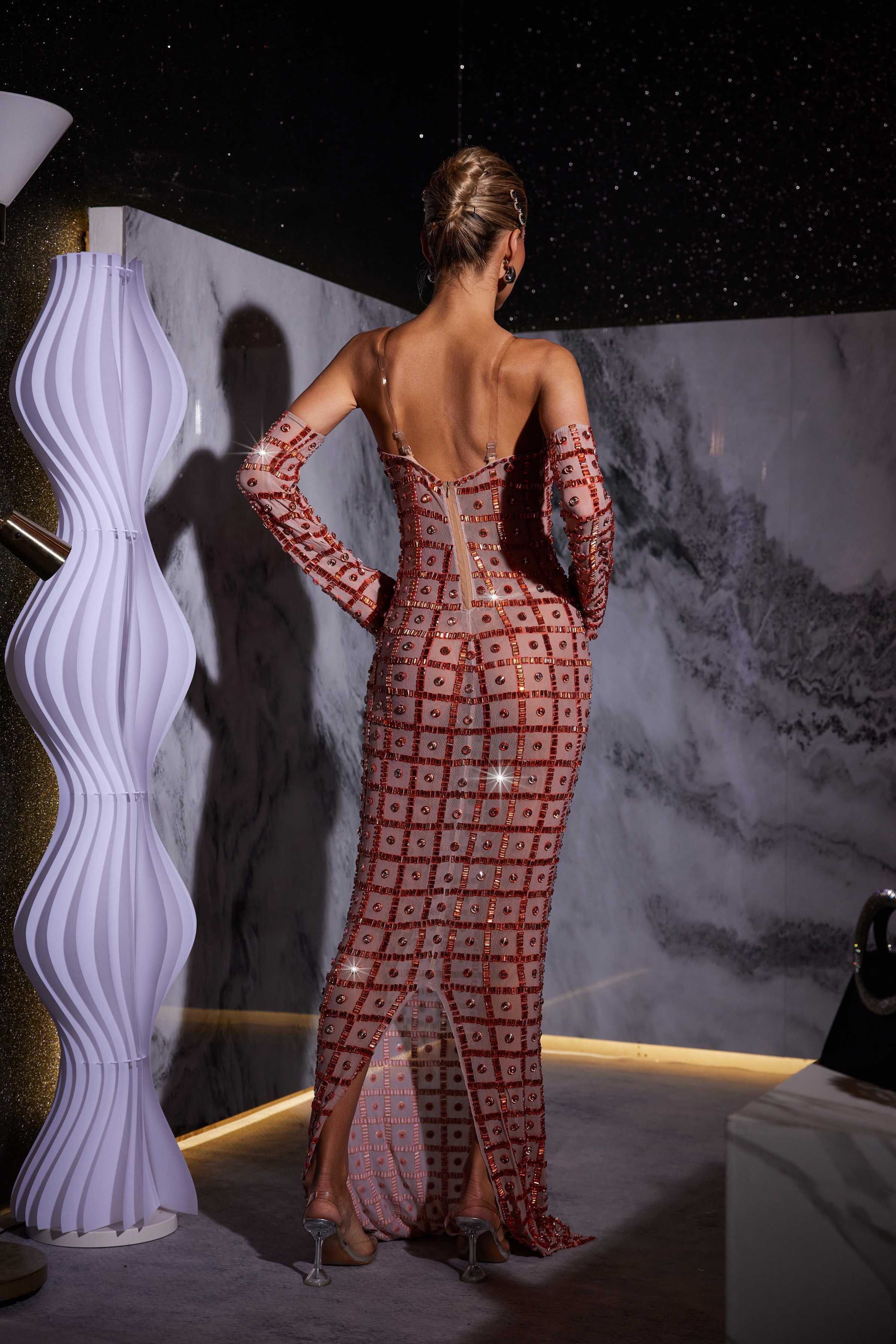 Stunning model in a nude Kieran Rhinestone Mesh Maxi Dress.  The strapless, sparkly maxi dress features intricate rhinestone detailing and a flowing mesh skirt. Perfect for prom or an elegant evening event.